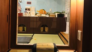 Una habitación japonesa tradicional con suelo de tatami, una cama de madera baja y una puerta corredera que da a un baño.