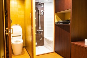 Ein kleines Badezimmer mit Toilette, Dusche und einem Holzkosmetikschrank.