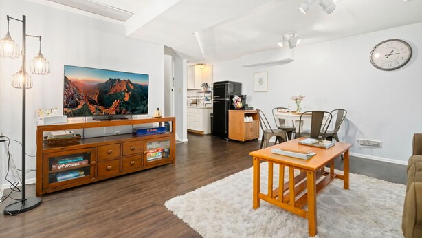 Un salon moderne doté d’un meuble de rangement en bois pour l’équipement audiovisuel, d’un téléviseur à écran plat et d’un coin repas avec une table et des chaises.