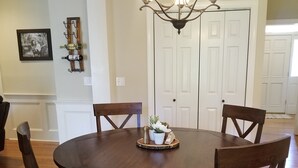 Une salle à manger avec une table ronde en bois, quatre chaises, un lustre et un tapis.
