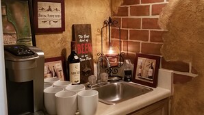 Une cuisine équipée d’une machine à café, de tasses blanches, d’un robinet à bière et d’une bougie.
