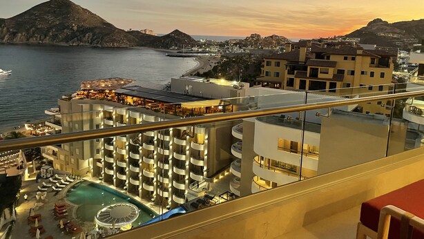 Un hotel con piscina, varios pisos y vistas al mar y al paisaje urbano.