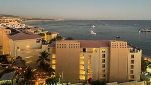 Un hotel frente al mar con varios balcones que dan al océano, una playa al fondo y varios barcos en el agua.