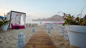 Decoración para una boda en la playa, con un paseo de madera, toldos blancos y zonas de estar.