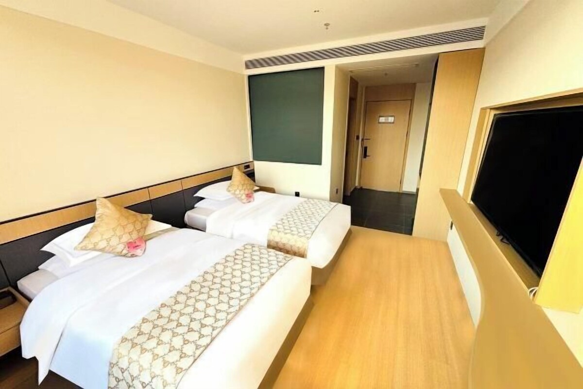 Une chambre d’hôtel avec deux lits, une télévision et une porte donnant sur une autre chambre.