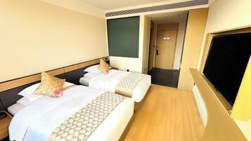 A hotel room with two beds, a TV, and a door leading to another room.