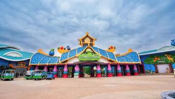 A colorful building with a central entrance, surrounded by a parking area with vehicles.