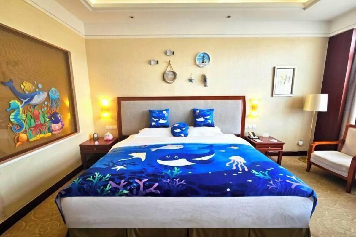 A hotel room with a bed, nightstands, a chair, a painting, and wall decorations.