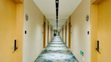 A hotel hallway with a patterned carpet, wooden doors, and a long corridor.