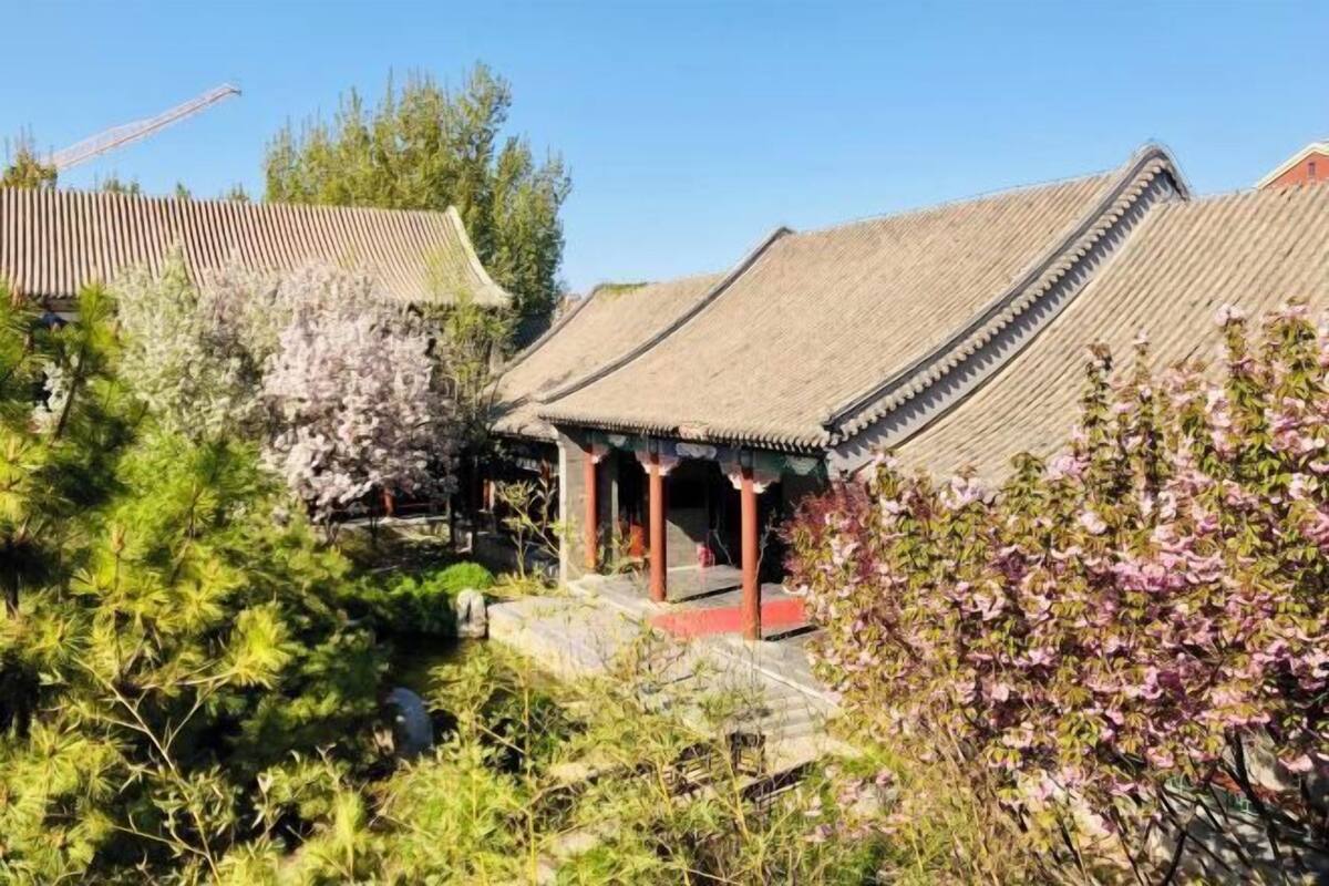 A traditional building with a tiled roof, a covered entrance, and a stone pathway leading to it.