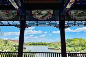 A pavilion with traditional Chinese architectural elements, a view of a lake, and boats.