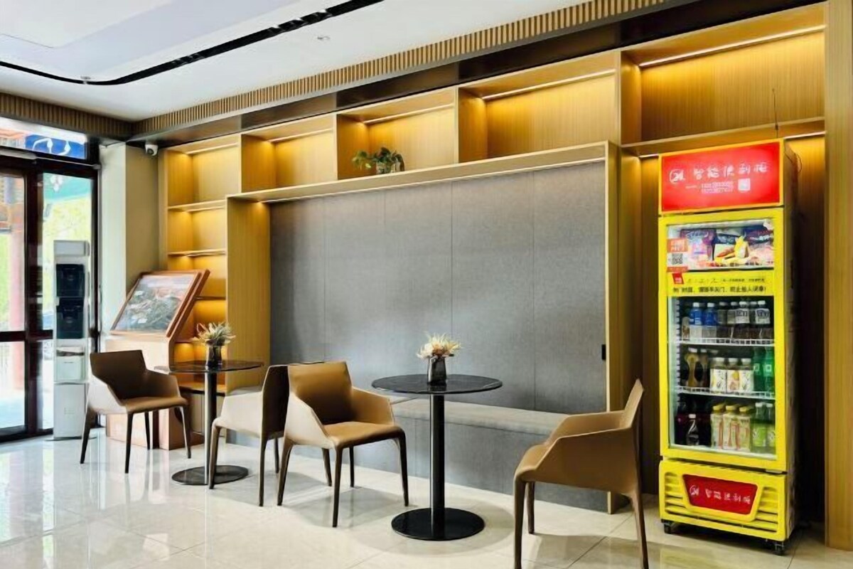 Un intérieur moderne avec des espaces aménagés pour s’asseoir, un distributeur automatique et un tableau de menu numérique.