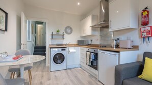 Une cuisine compacte équipée d’un lave-linge, d’un four à micro-ondes, d’un grille-pain et d’un four.