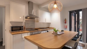 Une cuisine moderne avec des armoires blanches, des appareils en acier inoxydable et un îlot central en bois.