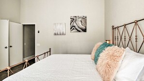 Une chambre à coucher comprenant un lit, une armoire et deux œuvres d’art abstraites accrochées au mur.