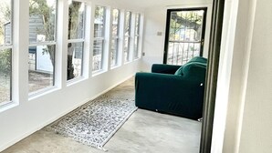 Un'ampia stanza con grandi finestre, un divano verde e un tappeto decorato.