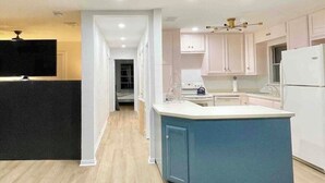 Una cucina moderna con mobili bianchi, un'isola blu e un frigorifero bianco.