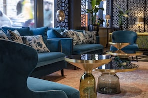Un soggiorno moderno con un divano blu, un tavolino da caffè in vetro e un vaso decorativo.