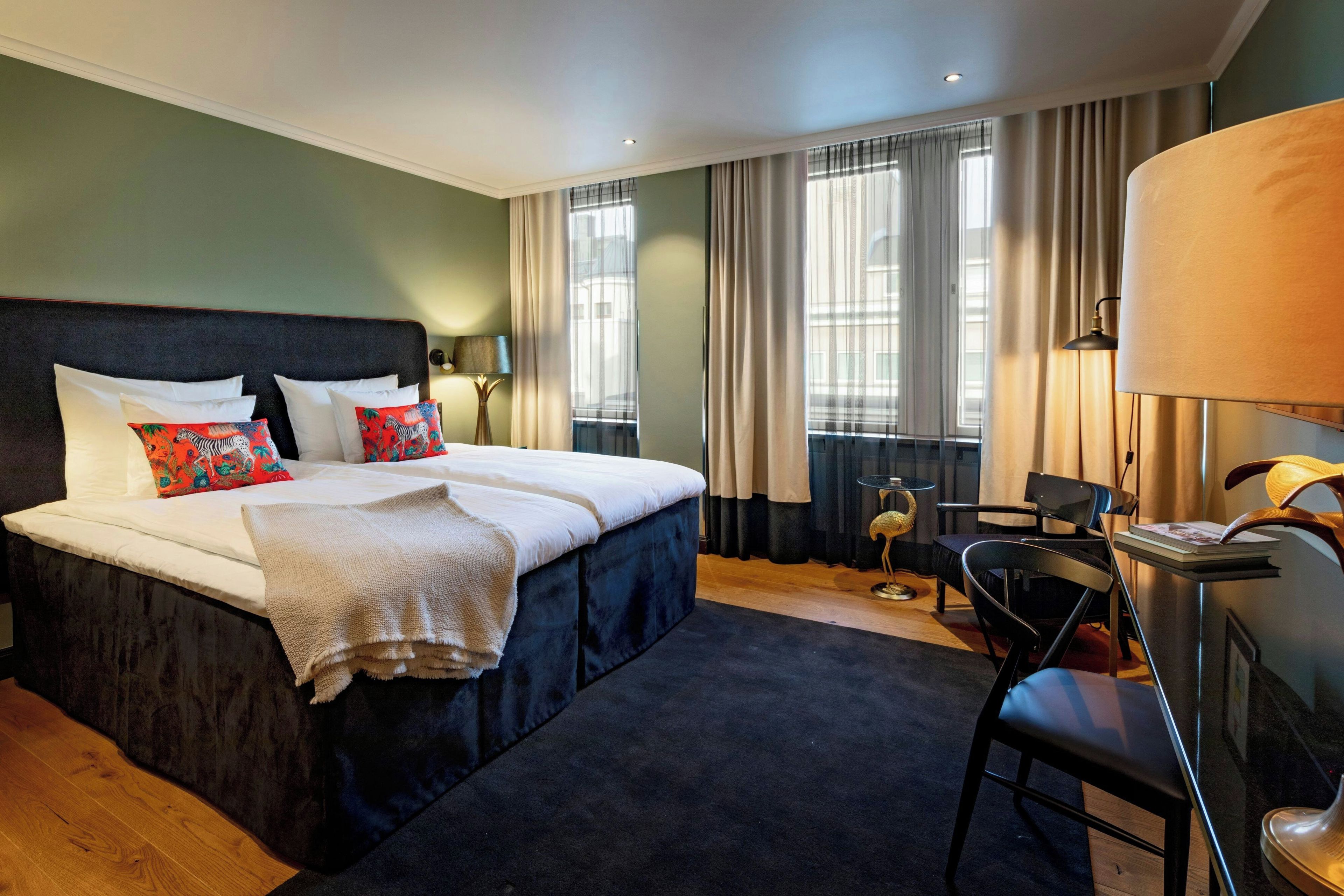 A hotel room with a large bed, a desk, and a chair.