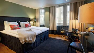 A hotel room with a large bed, a desk, and a chair.