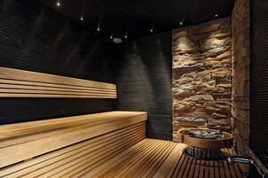 Una sauna con panche in legno, una parete in pietra e un braciere.