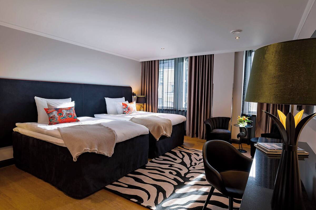 Una camera d'albergo moderna con un letto grande, una scrivania e un tappeto a motivi zebrati.