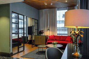 A modern living room with a red sofa, a black armchair, a small round table, and a lamp.