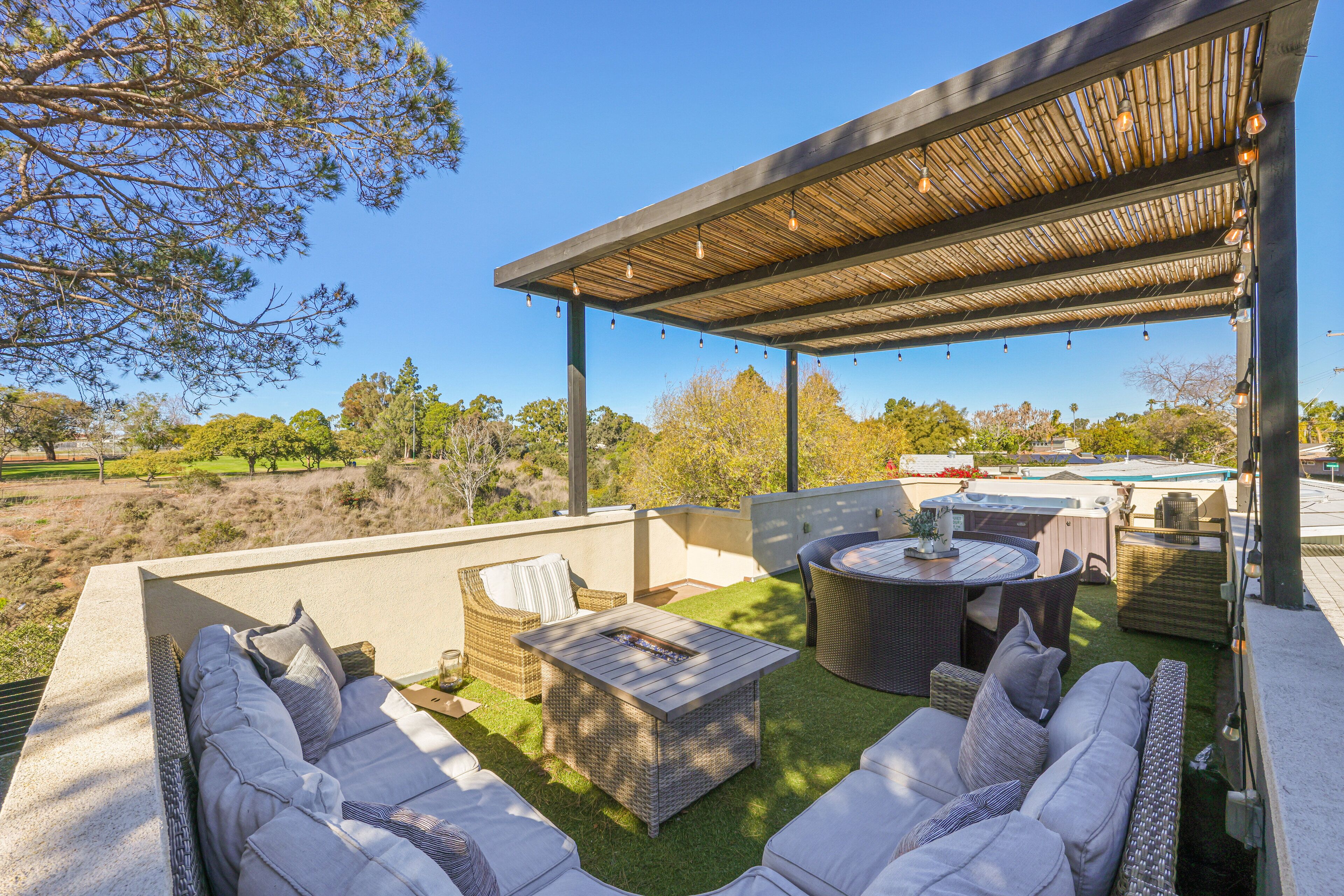 An outdoor patio with a covered seating area, a fire pit, and a pool.