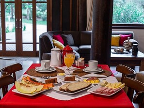 A breakfast table set with various dishes, a coffee pot, and a glass of orange juice. - Aires de Patagônia Pousada (Cambara do Sul)