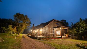 A rustic barn-style building with a porch and a gravel driveway.
