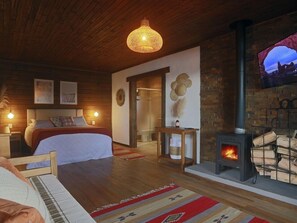A cozy bedroom with a bed, a wooden ceiling, a fireplace, and a TV mounted on the wall. - Aires de Patagônia Pousada (Cambara do Sul)