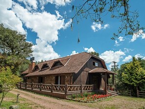 A rustic wooden building with a sloped roof, multiple windows, and a fenced porch area. - Aires de Patagônia Pousada (Cambara do Sul)