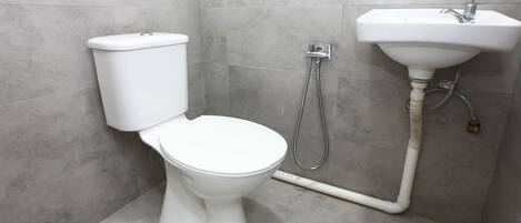 A bathroom with a toilet, a shower, and a sink.