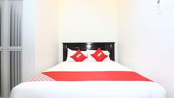 A bed with a white and red bedspread, two red pillows with "OYO" text, and a black headboard.