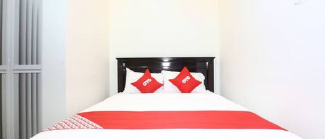 A bed with a white and red bedspread, two red pillows with "OYO" text, and a black headboard.