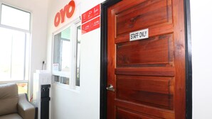 Entrada de hotel con puerta de madera que indica "STAFF ONLY", una ventana con letrero de "OYO" y un sofá al frente.
