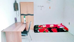 Une pièce comprenant un bureau en bois, une chaise, une armoire et un lit recouvert d’une couvre-lit à motifs floraux.