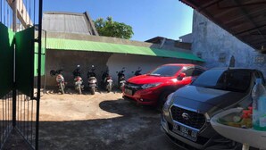 Un espace de stationnement où se trouvent plusieurs motos et une voiture rouge.