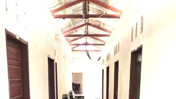 Un couloir dont le sol est recouvert de carreaux et où l’on trouve des portes en bois de chaque côté.