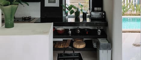 A modern kitchen with a black backsplash, white countertops, and a view of the outdoor swimming pool.