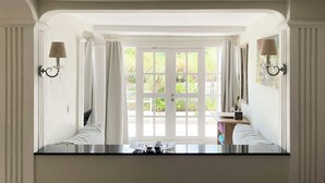 A bathroom with a large window, white walls, and two wall-mounted lamps. - Casa Artista By Villa Kresna (Seminyak)