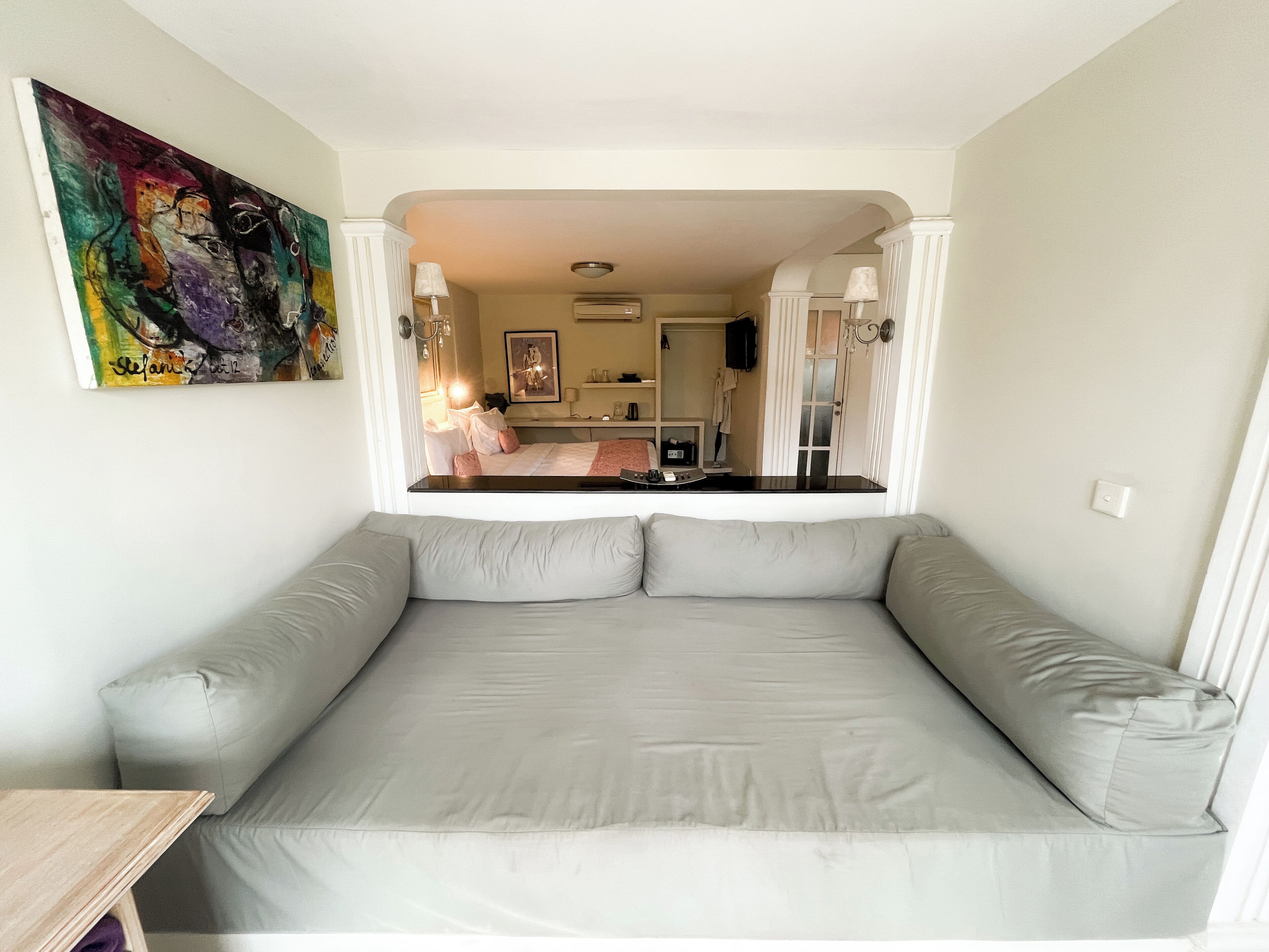 Et moderne værelse med en stor grå sofa, et billede på væggen og udsigt til soveområdet.