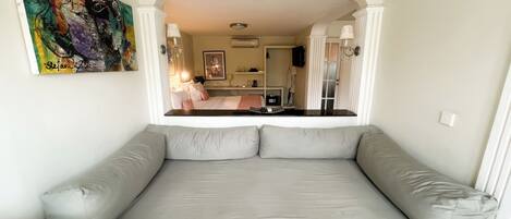 Et moderne værelse med en stor grå sofa, et billede på væggen og udsigt til soveområdet.