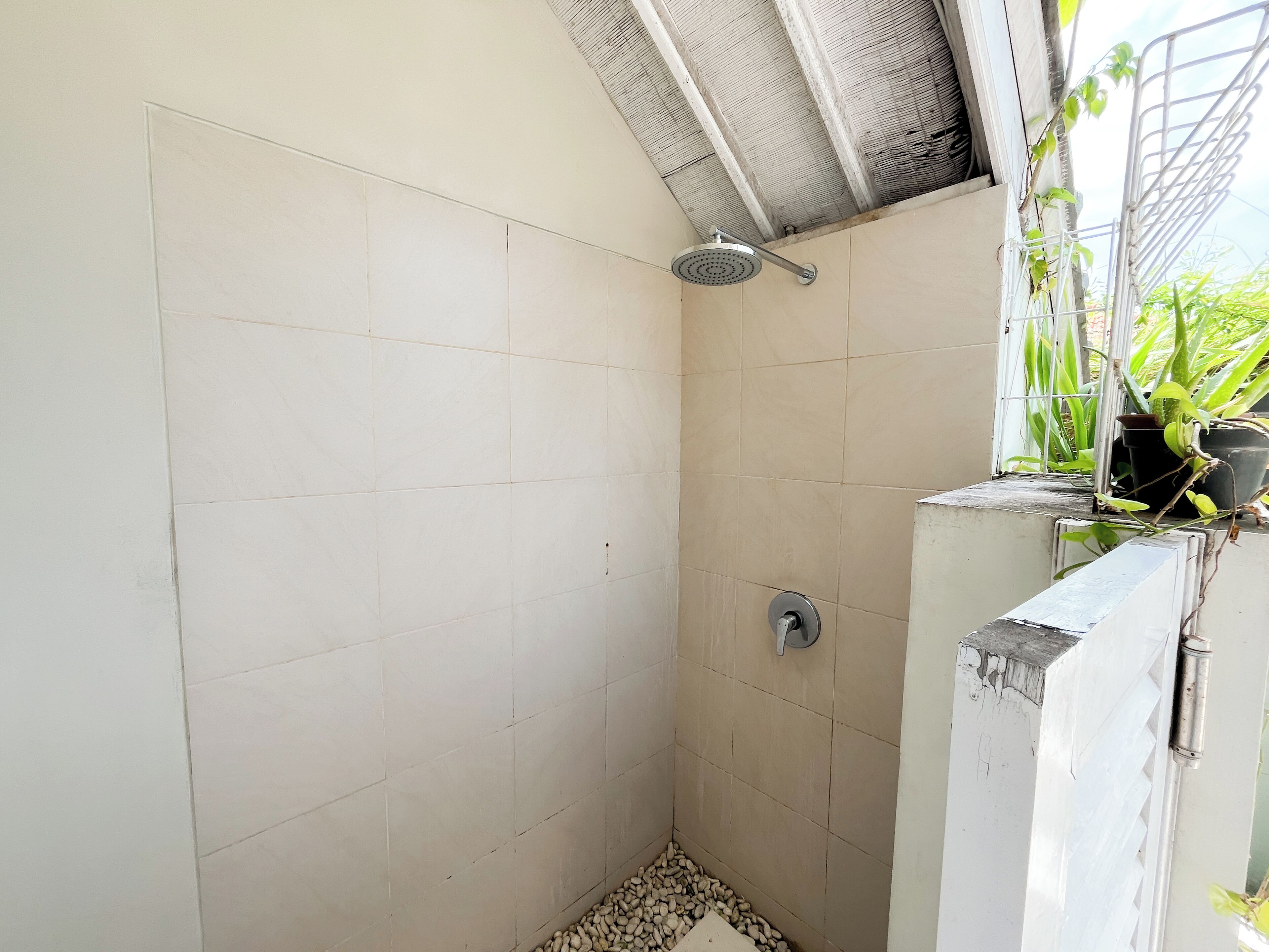 Un área de ducha pequeña y cerrada con paredes de azulejos y techo inclinado.