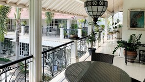 A covered outdoor area with a table and chairs, surrounded by potted plants and a hanging lantern. - Casa Artista By Villa Kresna (Seminyak)
