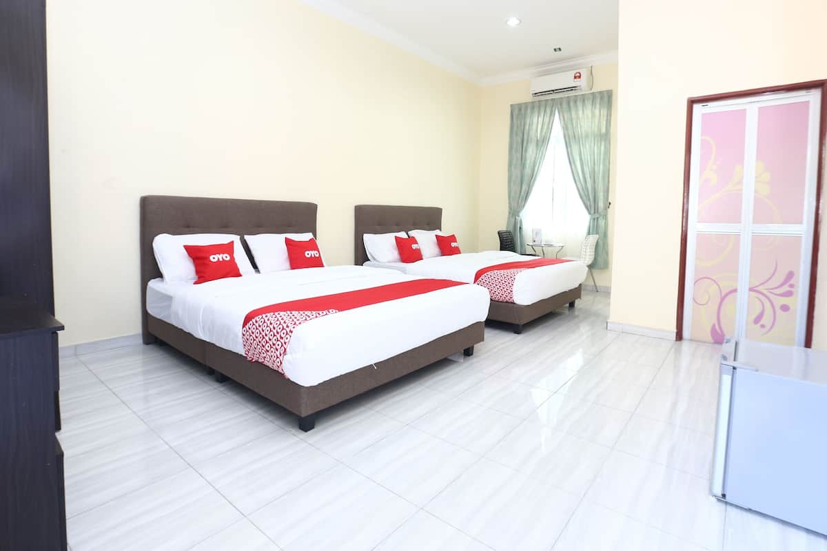 Habitación de hotel con dos camas, cada una con ropa de cama blanca y almohadas rojas, una mesita y una ventana con cortinas.