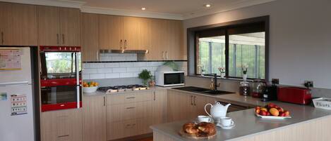 A modern kitchen with wooden cabinets, a built-in oven, a microwave, and a large window.