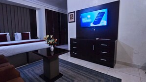 Een hotelkamer met een bed, een televisie, een bureau en een kledingkast.
