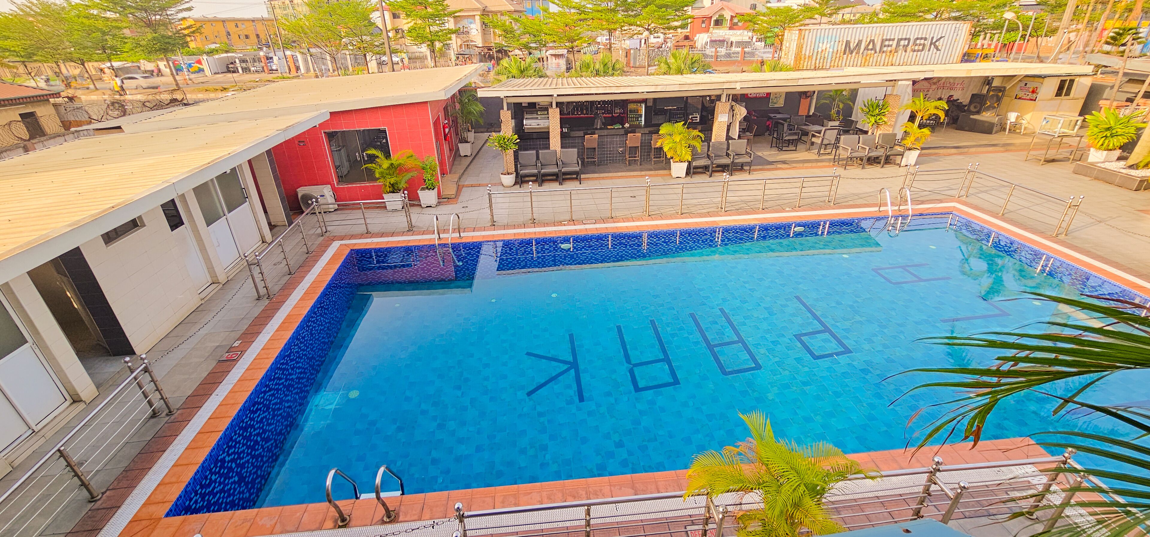 A swimming pool with a tiled border and a bar area with outdoor seating.