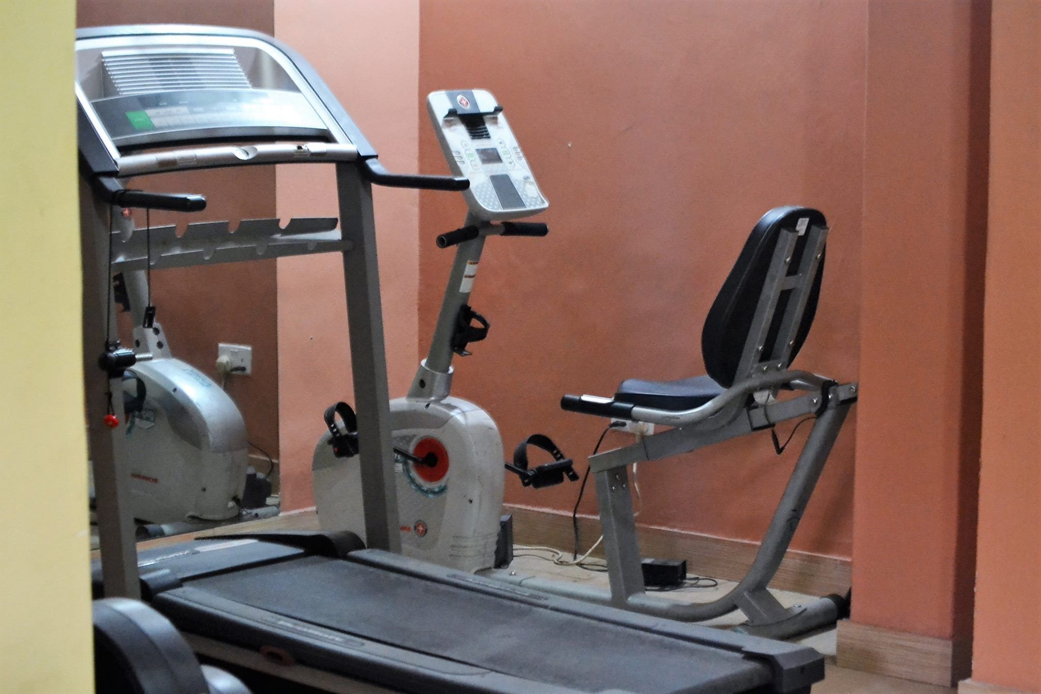 A gym with exercise equipment including a treadmill, a stationary bike, and a weight bench.
